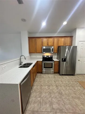 a kitchen with stainless steel appliances granite countertop a sink a stove a refrigerator a washer dryer and a dining table