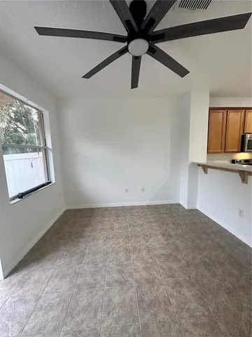 a view of a big room with wooden floor a ceiling fan and windows