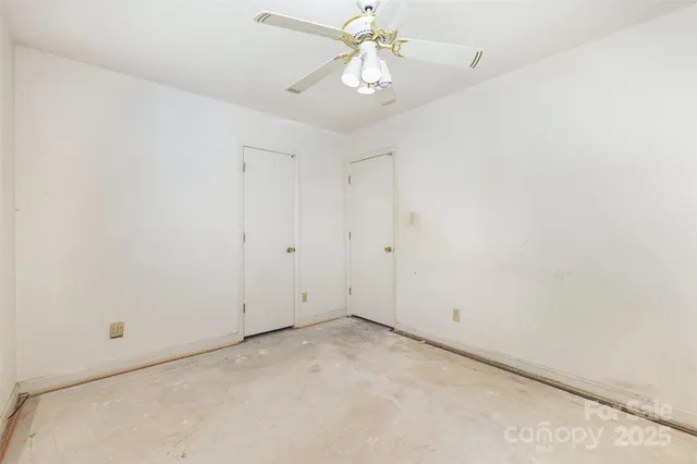 an empty room with a chandelier fan and closet area