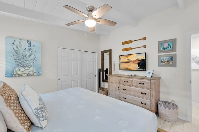 a bedroom with a bed and a flat tv screen on dresser