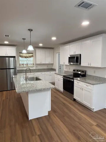 a large kitchen with granite countertop a stove top oven a sink dishwasher a dining table and chairs with wooden floor