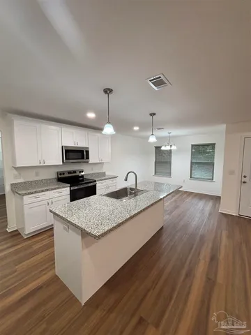 a large kitchen with granite countertop a stove top oven a sink a counter space and cabinets