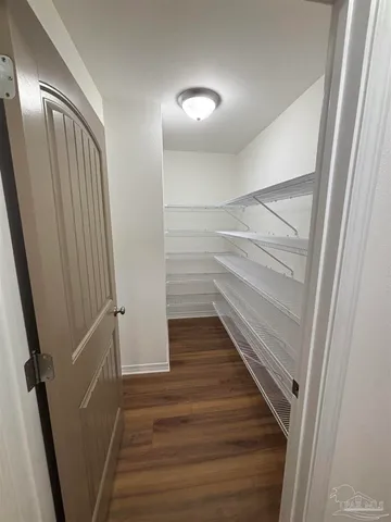 an empty room with wooden floor chandelier fan and windows