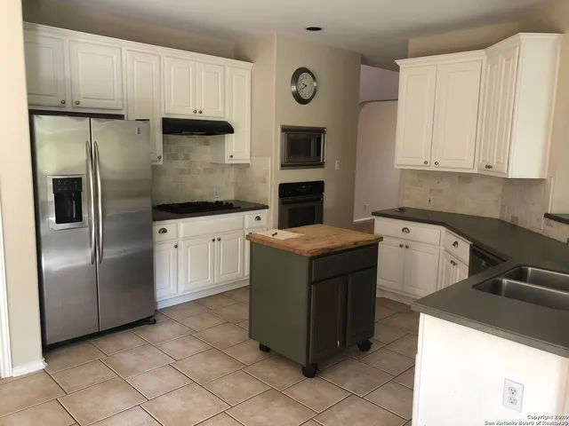 a kitchen with stainless steel appliances granite countertop a refrigerator a sink a stove and white cabinets