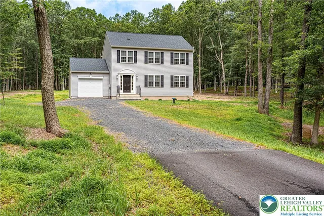 a view of a house with a big yard and large tree