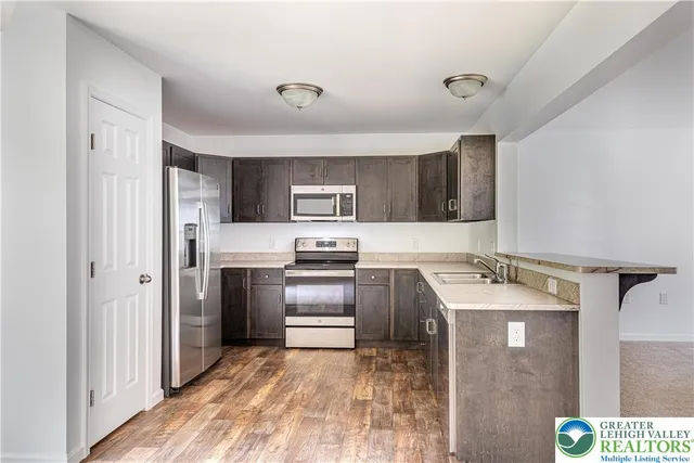 a kitchen with stainless steel appliances granite countertop a refrigerator sink and stove
