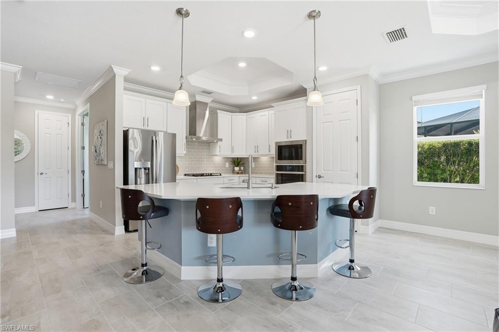 15194 Blue Bay Circle Fort Myers, FL 33913 - Photo 15 of 50 a kitchen with stainless steel appliances kitchen island granite countertop a refrigerator a stove a kitchen island a dining table and chairs