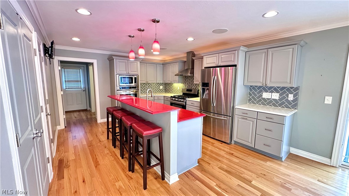 2603 Rockefeller Road Wickliffe, OH 44092 - Photo 5 of 34 Kitchen featuring hardwood flooring, stainless steel appliances, light gray cabinetry, and a bright red kitchen island with pendant lighting