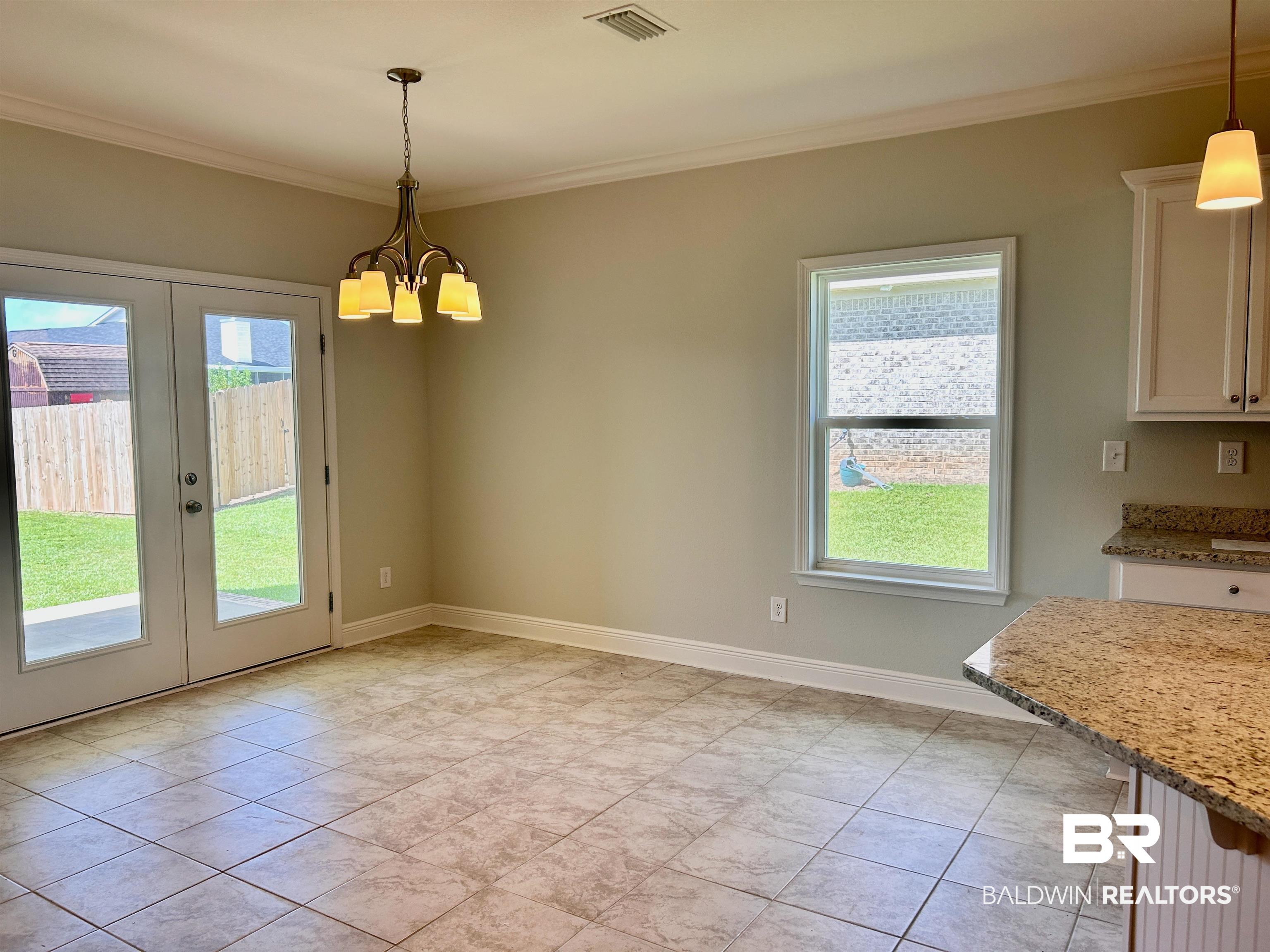 1267 Pembroke Way Foley, AL 36535 - Photo 12 of 17 Unfurnished dining area featuring crown molding, an inviting chandelier, and light tile patterned floors