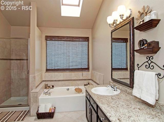 7831 Swiftrun Road Colorado Springs, CO 80920 - Photo 25 of 35 master bathroom has granite counter, tile floor, double sinks, large soaking tub, tiled shower w/glass door... plus a separate toilet area