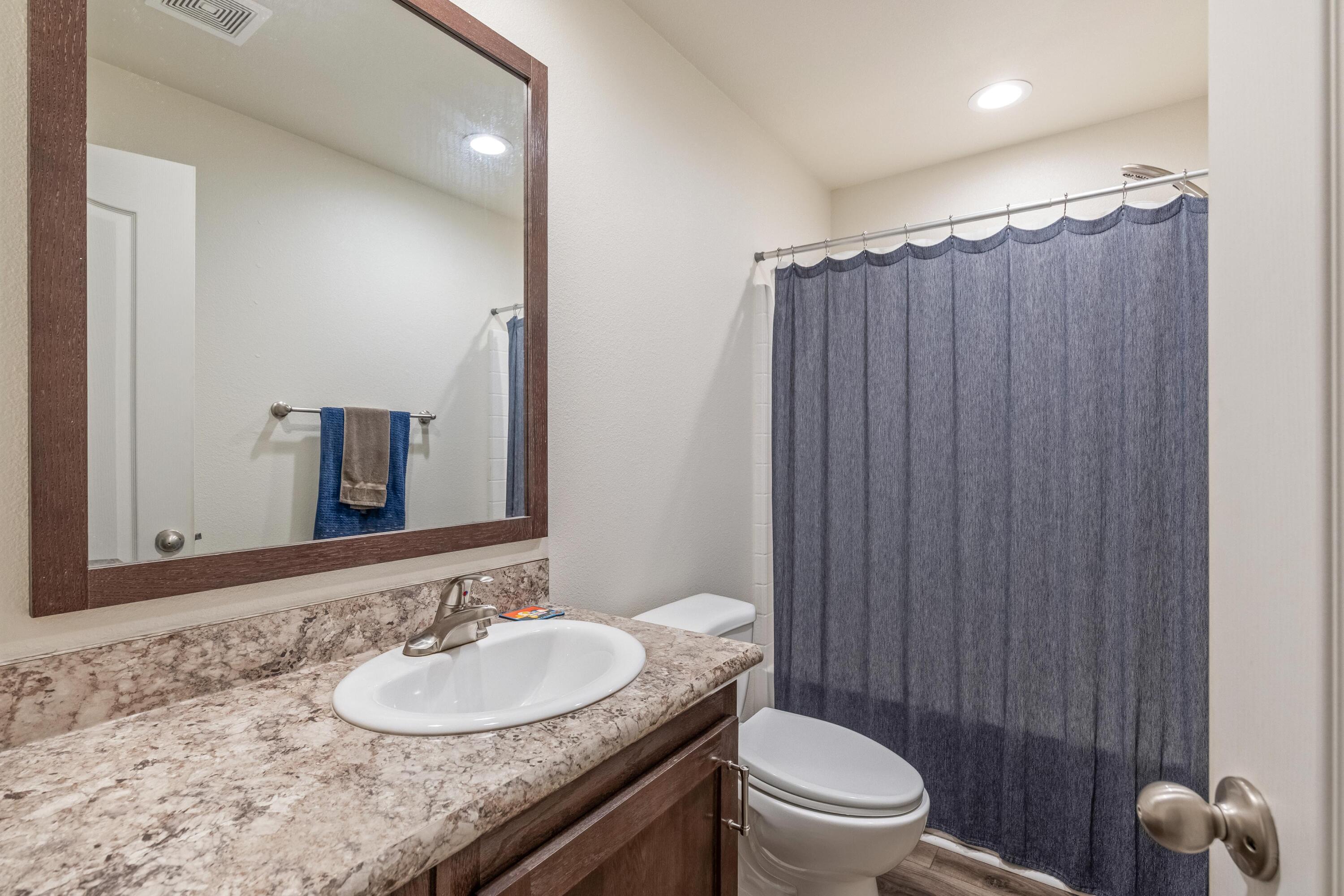 55823 Snow Goose Road Bend, OR 97707 - Photo 18 of 36 a bathroom with a granite countertop sink toilet a mirror and shower curtain