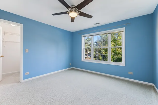 an empty room with windows and ceiling fan