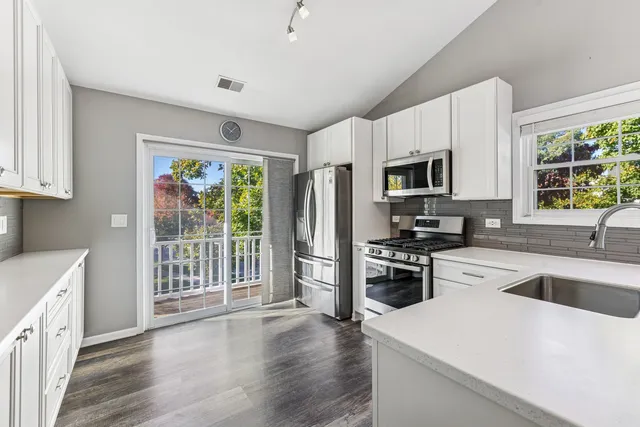 a kitchen with granite countertop a refrigerator stove top oven and sink