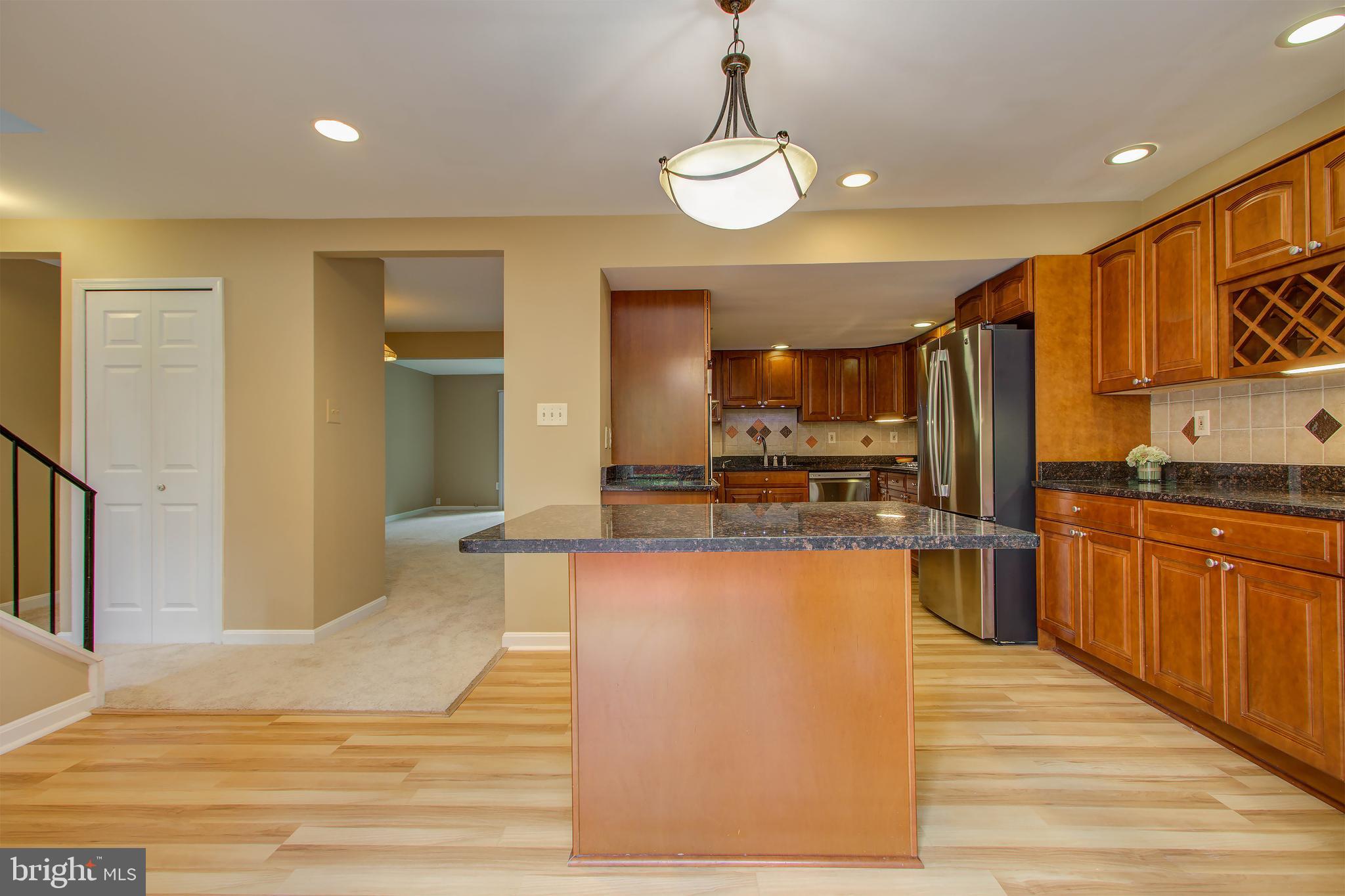 11024 Saffold Way Reston, VA 20190 - Photo 11 of 50 a large kitchen with stainless steel appliances kitchen island granite countertop a refrigerator a stove and a wooden floors