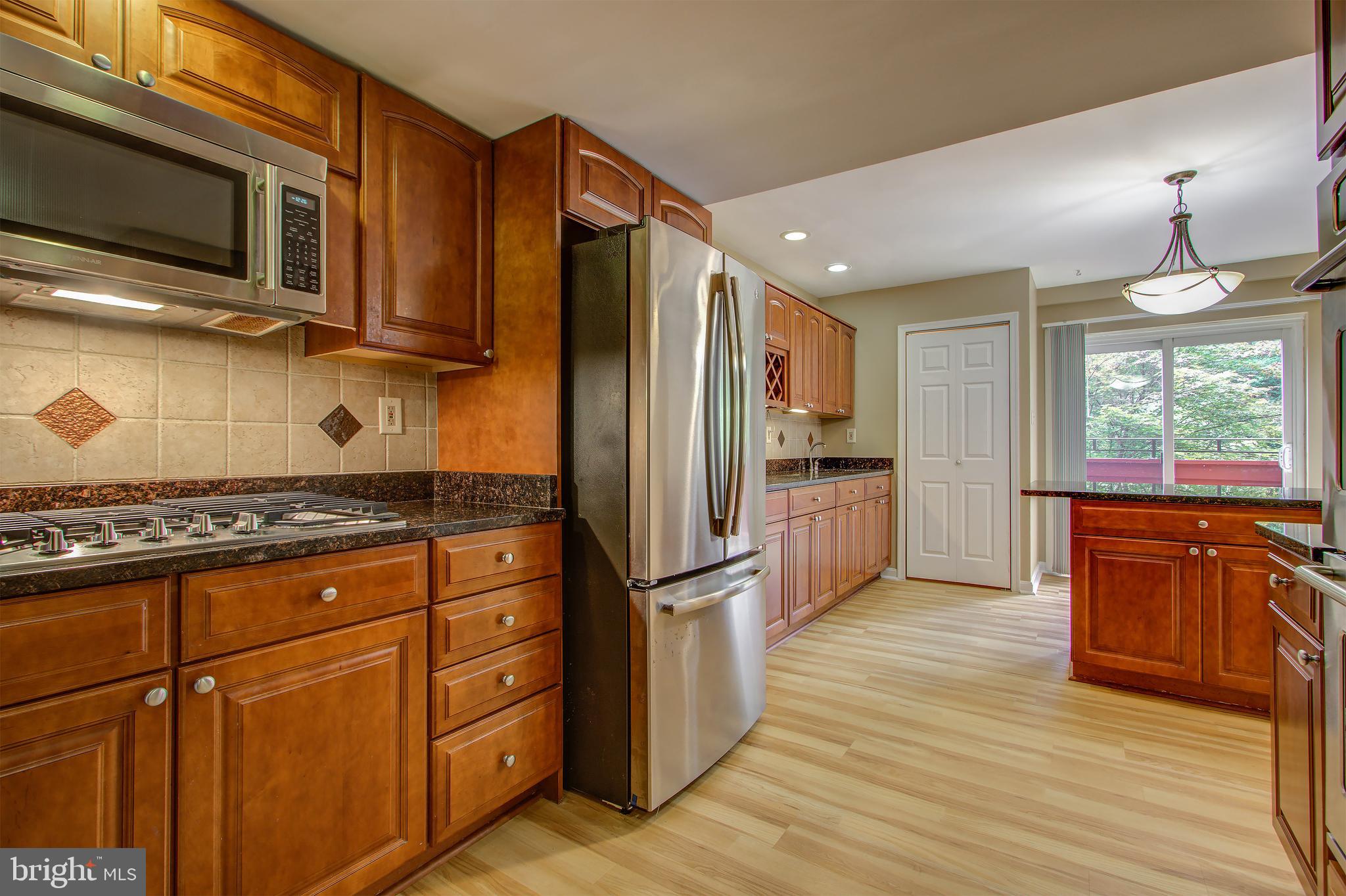 11024 Saffold Way Reston, VA 20190 - Photo 8 of 50 a kitchen with stainless steel appliances granite countertop a refrigerator a stove a sink and a microwave