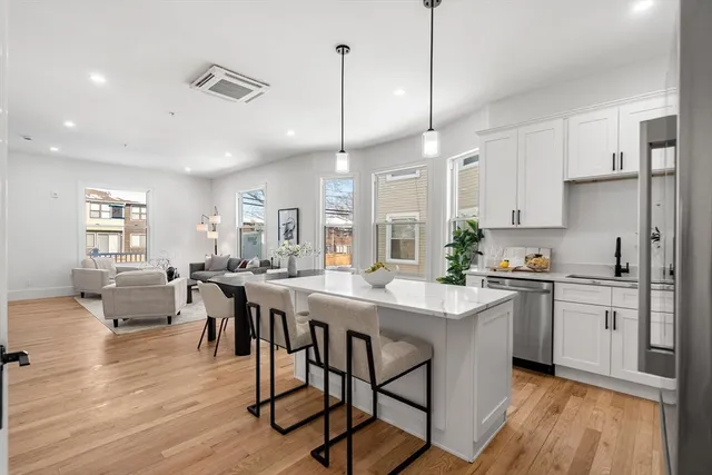 a kitchen with stainless steel appliances granite countertop a stove a sink a refrigerator and white cabinets with wooden floor