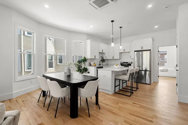 a kitchen with stainless steel appliances kitchen island granite countertop a dining table chairs and white cabinets