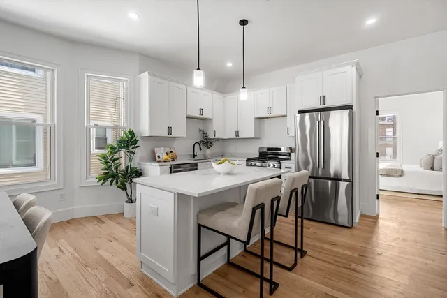 a kitchen with stainless steel appliances granite countertop a refrigerator a sink a stove a dining table and chairs