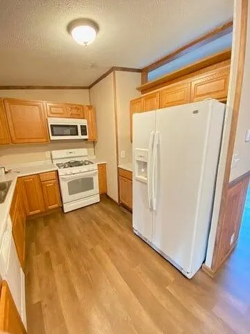 a view of a refrigerator in kitchen and an empty room