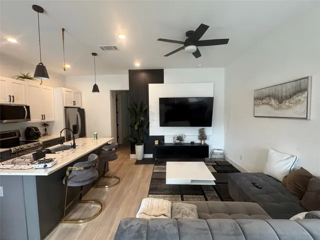 a living room with couches a flat screen tv and kitchen view
