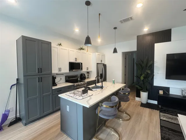 a kitchen with a refrigerator a sink and a stove top oven with wooden floor