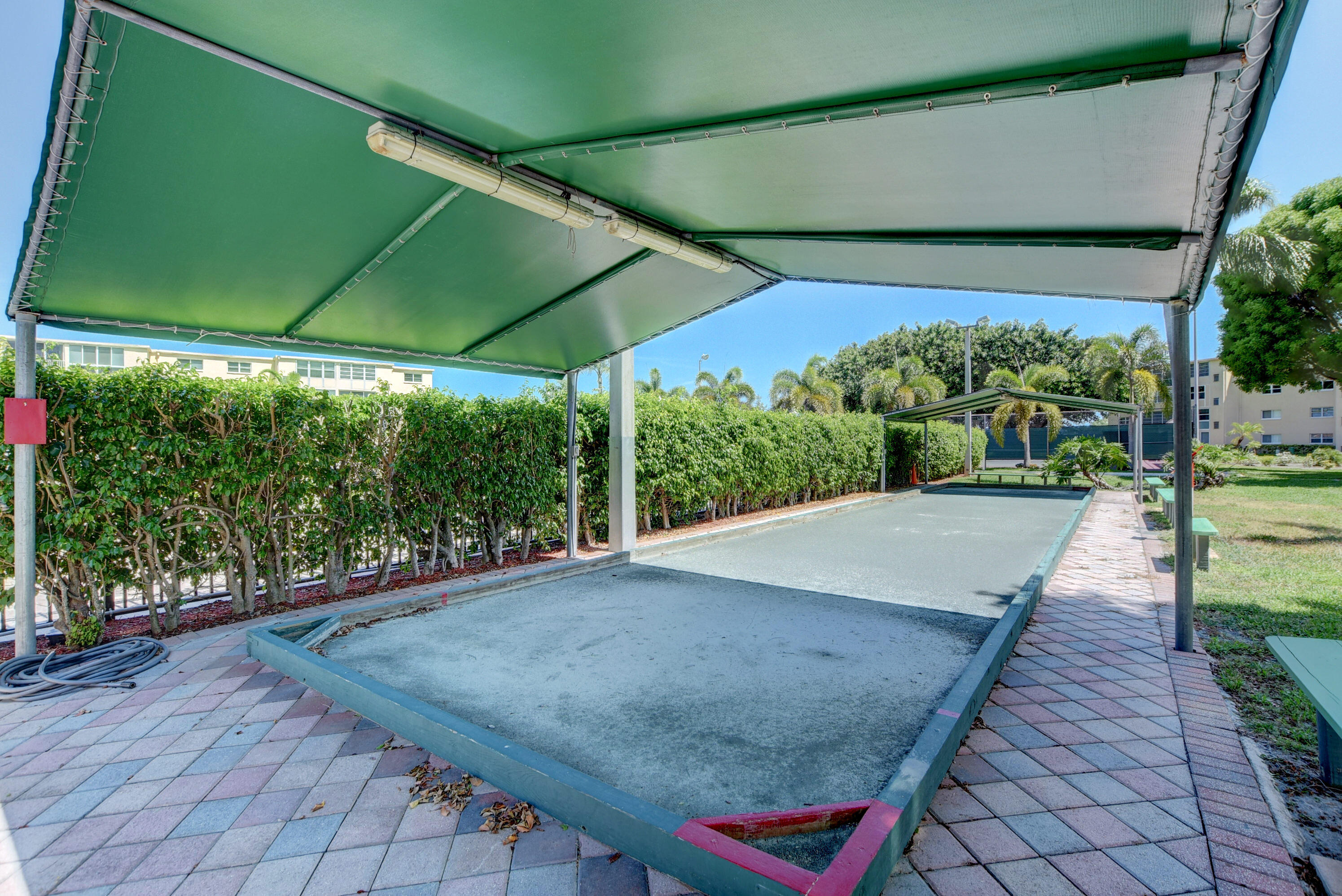 2620 Northeast 1st Court, Unit 403 Boynton Beach, FL 33435 - Photo 24 of 42 a view of a backyard with table and chairs under an umbrella