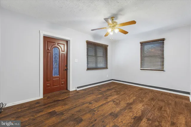 a view of an empty room with window and wooden floor
