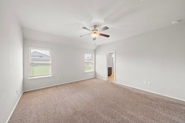 an empty room with a chandelier fan and windows