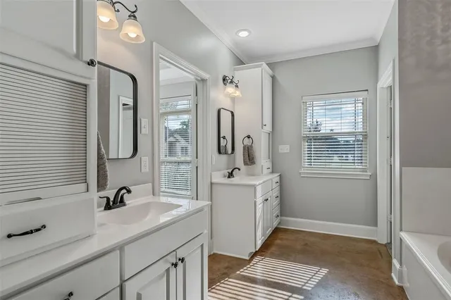a spacious bathroom with a double vanity sink a mirror and next to a window