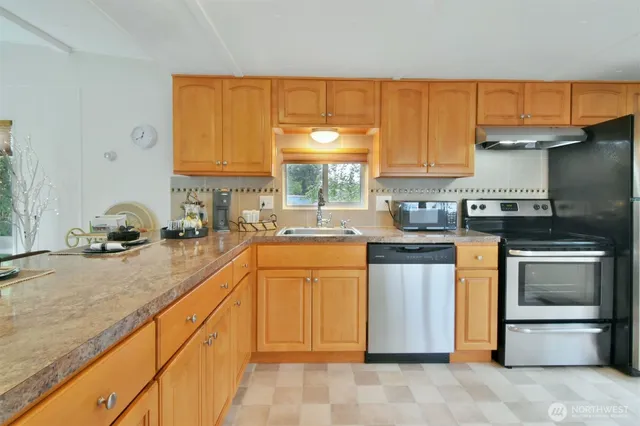 a kitchen with stainless steel appliances granite countertop a stove sink and cabinets