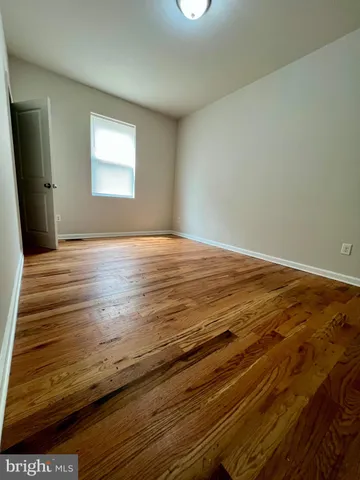 a view of empty room with window and wooden floor