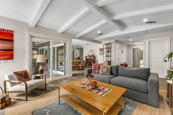 a kitchen with kitchen island granite countertop a stove a sink a dining table chairs and white walls