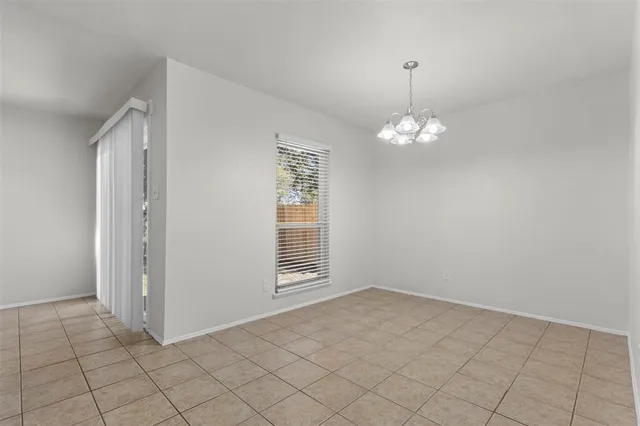 en empty room with windows and chandelier