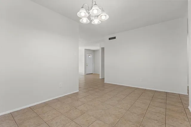 a view of an empty room with a chandelier fan