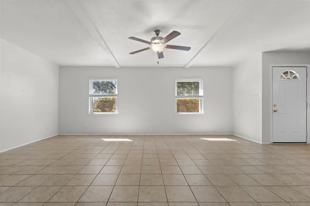 an empty room with windows and ceiling fan