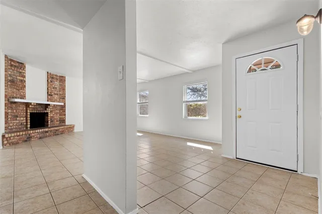 an empty room with windows and fireplace