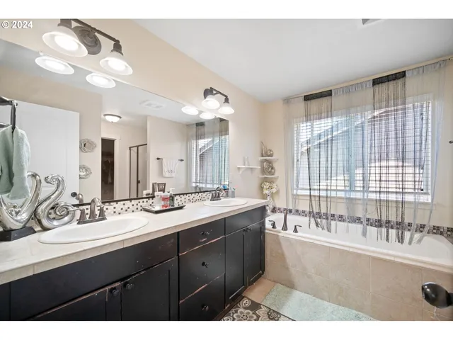 a bathroom with a sink double vanity granite tub shower and a mirror