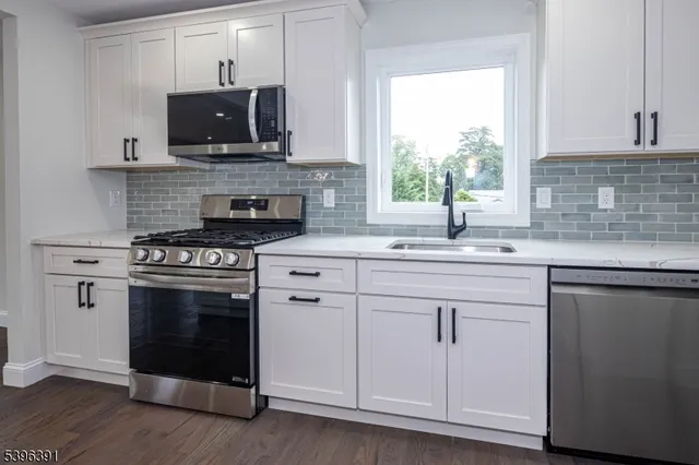 a kitchen with granite countertop a stove a sink and a microwave