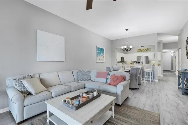 a living room with furniture kitchen view and a chandelier