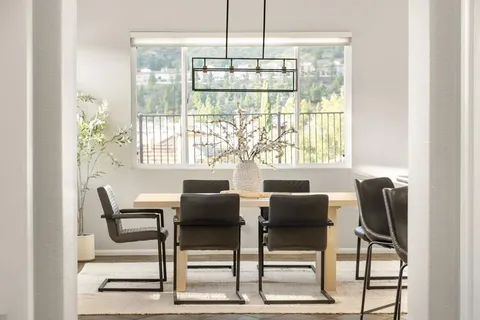 a kitchen with stainless steel appliances granite countertop a stove top oven a sink a dining table and chairs