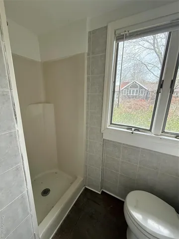a bathroom with a toilet a window and a shower