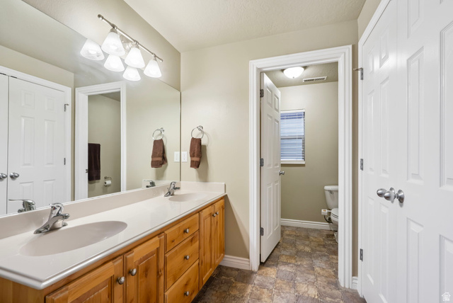 557 South 1470th Street East Springville, UT 84663 - Photo 31 of 46 Full bath featuring double vanity, stone finish floors, and a textured ceiling