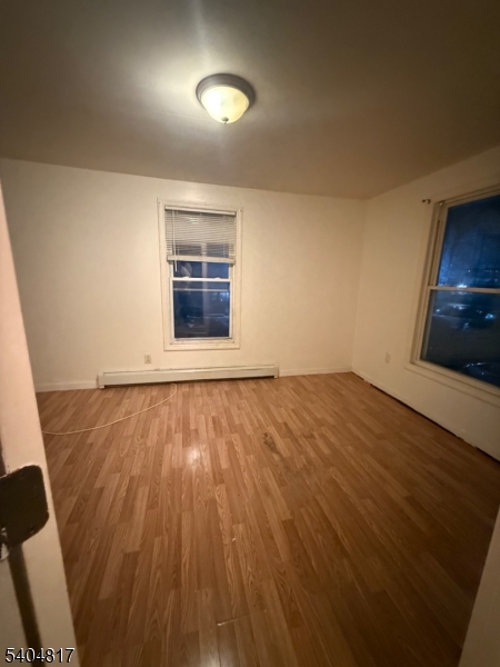 139 Stiles Street Elizabeth, NJ 07208 - Photo 6 of 9 an empty room with wooden floor and windows
