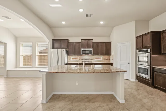 a kitchen with stainless steel appliances granite countertop a refrigerator and a stove