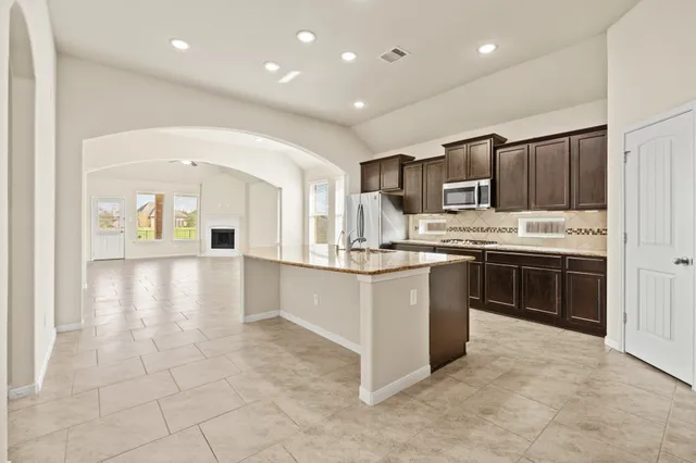 a kitchen with stainless steel appliances granite countertop a stove top oven a sink and a refrigerator