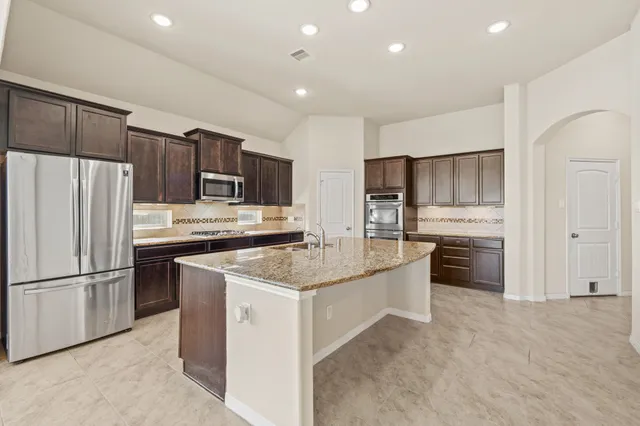 a kitchen with stainless steel appliances granite countertop a refrigerator sink and cabinets