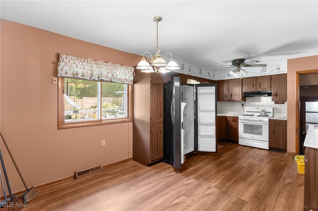 3907 Edwards Street Mineral Ridge, OH 44440 - Photo 24 of 45 Kitchen featuring light countertops, pendant lighting, tasteful backsplash, dark wood-type flooring, and white gas stove