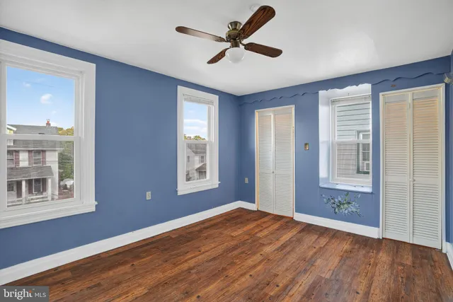 a view of empty room with wooden floor and fan