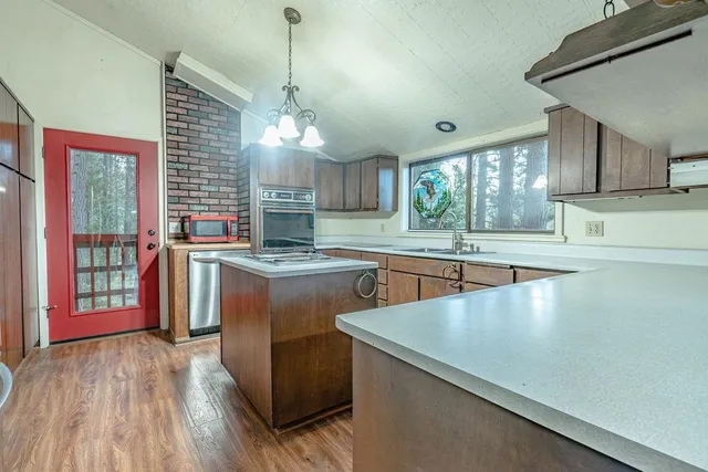 a kitchen with stainless steel appliances granite countertop a sink a stove and a wooden floors