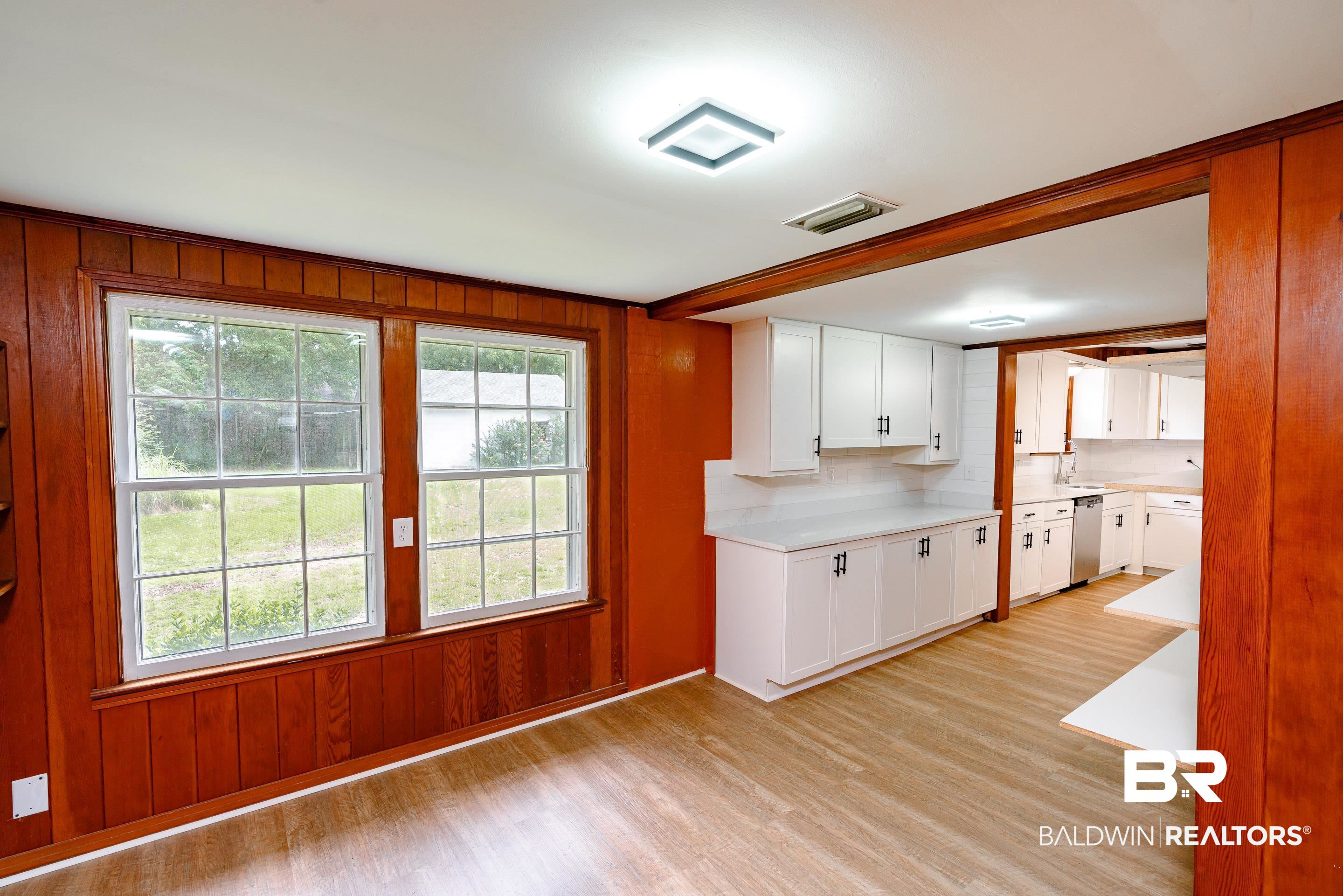 1160 Military Road Mount Vernon, AL 36560 - Photo 16 of 30 Kitchen with light hardwood / wood-style floors, white cabinetry, dishwasher, and wood walls